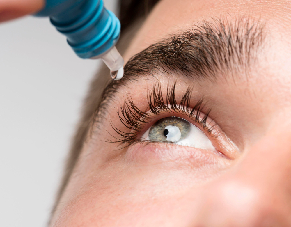Un homme aux yeux de couleur vert, est en train de mettre une goutte de produit ophtalmologique dans son oeil