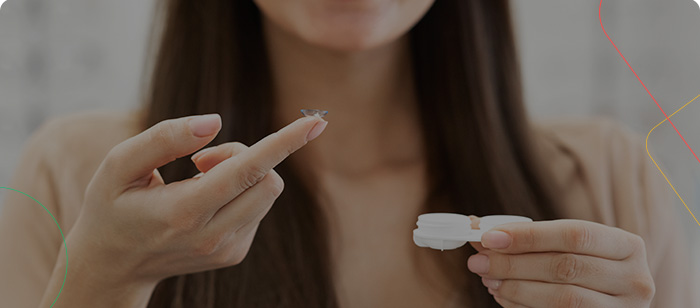 Une femme tient sur son doigt une seule lentille de contact