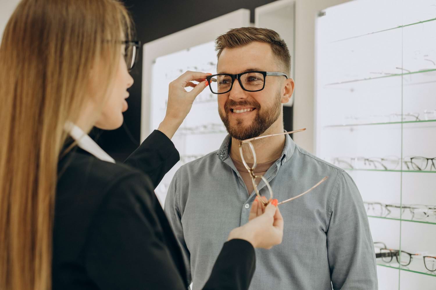 Un client choisit des lunettes dans un magasin d'optique avec l'aide d'un vendeur