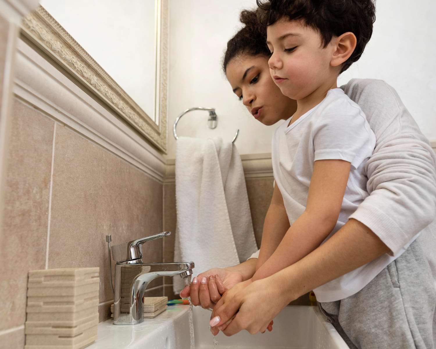 Mignon petit garçon se laver les mains avec sa maman