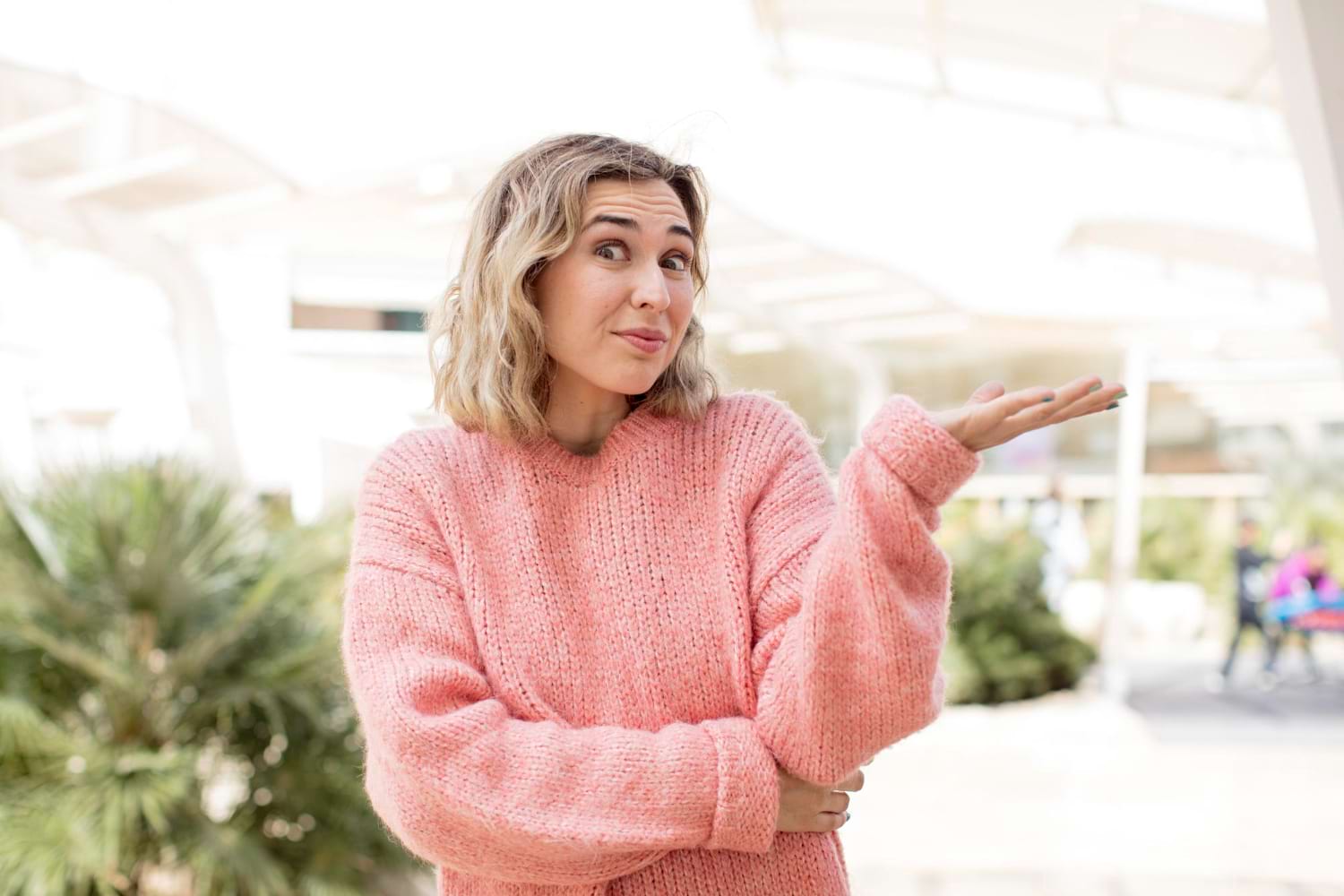 Femme avec un pull rose qui semble confuse