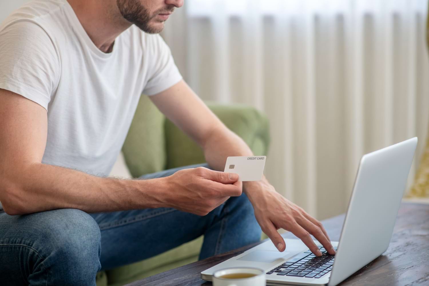 Homme assis qui paye avec sa carte de crédit